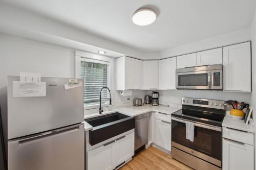 una cucina con armadietti bianchi ed elettrodomestici in acciaio inossidabile di Sleeping Bear Cozy Corner End Unit a North Creek