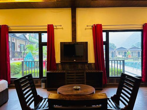 a living room with a tv and a table and chairs at DLS MJ River Resort, Rishikesh in Shivpuri