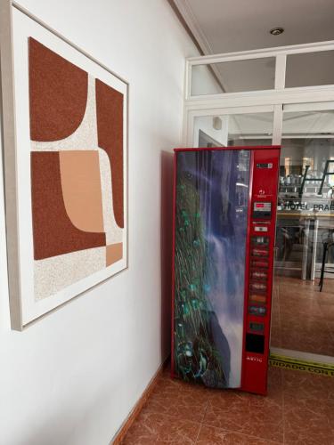 a red machine next to a wall with a picture at Hotel Praderón in San Sebastián de los Reyes