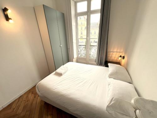un lit blanc dans une chambre avec une fenêtre dans l'établissement T3 rénové vue sur le centre de Rennes, à Rennes