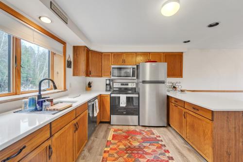 a kitchen with wooden cabinets and a stainless steel refrigerator at Moxham 58H - Adirondack Retreat Mountain Views in North Creek