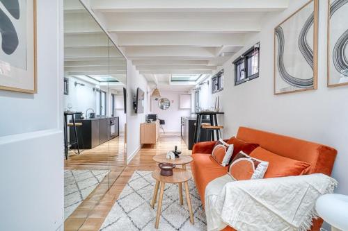 un salon avec un canapé orange et une table dans l'établissement Superbe Loft lumineux Paris Alesia- II, à Paris