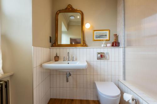a bathroom with a sink and a toilet and a mirror at The Beach House Boutique Hotel in Sunderland