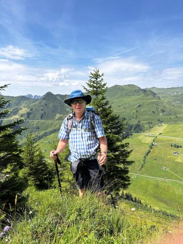 un homme avec un sac à dos debout au sommet d'une colline dans l'établissement Hotel Lucia - 3 Sterne Superior, à Damüls
