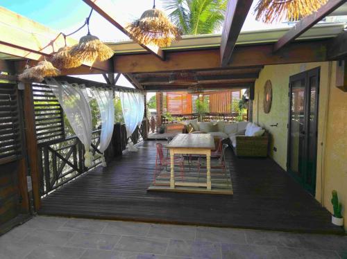 a wooden deck with a table and chairs on it at L'Echappée Tropicale -- L'échappée VERTE -- Oasis Bleu Lagon & Vert Forêt, T4 avec grande terrasse, à 5min de la plage in Étang-Salé les Bains
