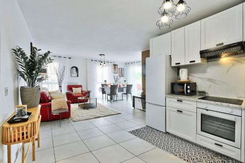 une cuisine avec des armoires blanches et un salon dans l'établissement L'Eden Urbain Proche Lyon, Terrasse, BBQ et Parking, à Grigny