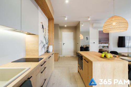 a kitchen with wooden cabinets and a counter with a bowl of fruit at Apartament TUKAN w SARBINOVE z garażem - 365PAM in Sarbinowo