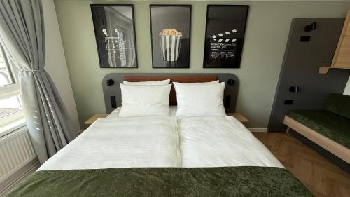a bed with white sheets and pillows in a room at Cinema City Hotel Europaplatz Karlsruhe - Brand New Boutique Hotel 2025 - in Karlsruhe