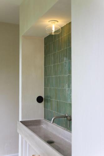 La salle de bains est pourvue d'un lavabo et d'un mur carrelé vert. dans l'établissement Maison d’hôte Les Grands Chênes, à Valojoulx