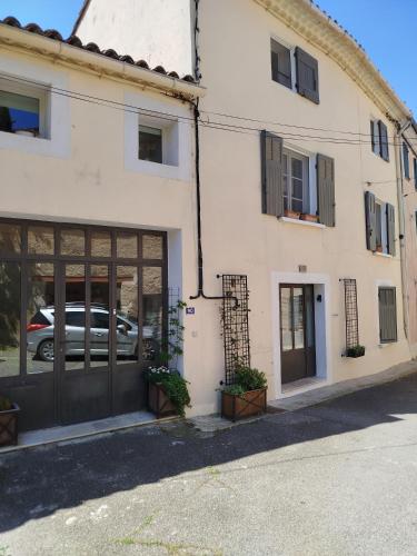 a white building with a garage and a car at A l'Ombre de la Dame in Cucuron