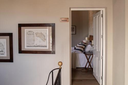 a hallway with a room with a bed and framed maps at Binissaida Boutique Hotel in Es Castell