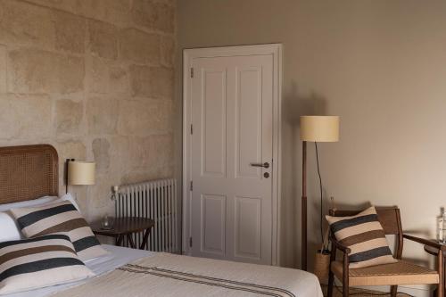 a bedroom with a bed with two chairs and a door at Binissaida Boutique Hotel in Es Castell