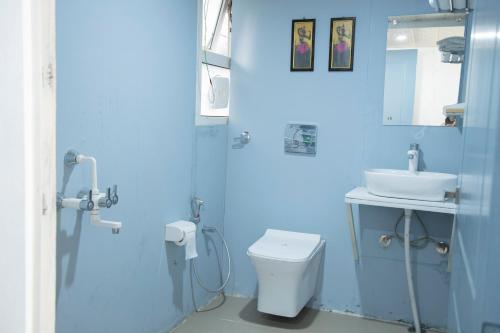 a blue bathroom with a toilet and a sink at The Acanti, Dharamshala in Dharamshala