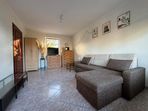 a living room with a couch and a television at Apartament Juratka in Jurata