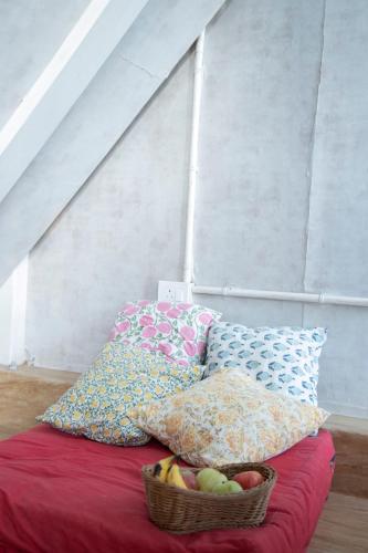 a basket of fruit sitting on a bed with pillows at The Acanti, Dharamshala in Dharamshala