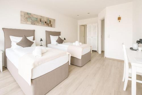 two beds in a white bedroom with a table at Landhaus Chica in Salzgitter