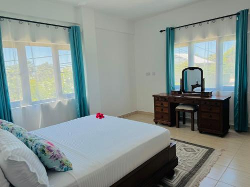a bedroom with a bed and a dresser with a mirror at Bijoutier Apartments in Grand'Anse Praslin