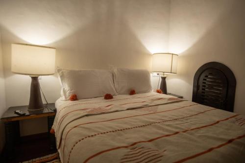 a bedroom with a large bed with two lamps at Dar Lalzohra in Rabat
