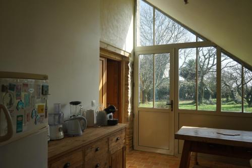 Il comprend une cuisine équipée d'un réfrigérateur et d'une fenêtre. dans l'établissement Les communs du manoir, à Loc-Maria-Plouzané