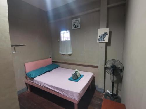 a small bed in a room with a fan at Ken's Inn in Coron