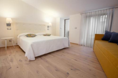 a bedroom with a white bed and a couch at Hotel Il Palazzo in Assisi