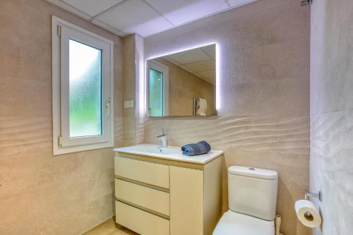 Un baño con inodoro, lavabo y espejo. en Casa Lorraine, en Mijas