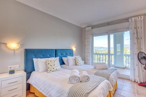 Dos camas en un dormitorio con una gran ventana. en Casa Lorraine, en Mijas