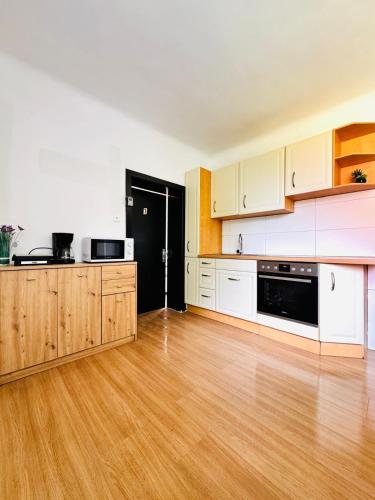 an empty kitchen with white cabinets and a wooden floor at Spacious 6BR Shared Villa with Garden near Danube For 16 Guests in Vienna