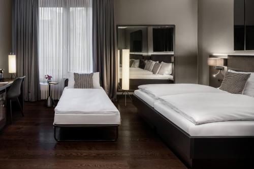 a hotel room with two beds and a mirror at Hotel AMANO Düsseldorf in Düsseldorf