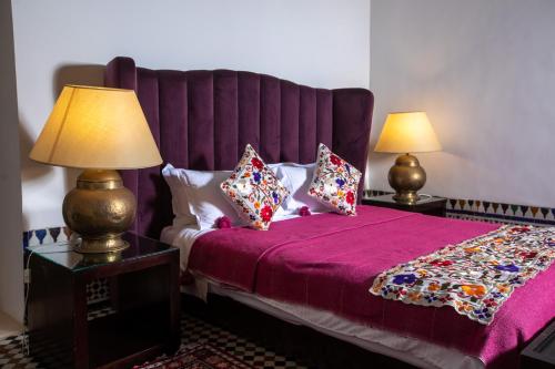 a bedroom with a purple bed with pillows and two lamps at Dar Lalzohra in Rabat