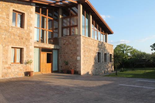 a brick building with a orange door and a parking lot at Casa Rural La Flor del Naranjo in Cadalso