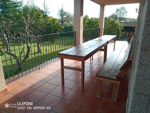 a wooden table and two benches on a balcony at Casa Rural La Flor del Naranjo in Cadalso