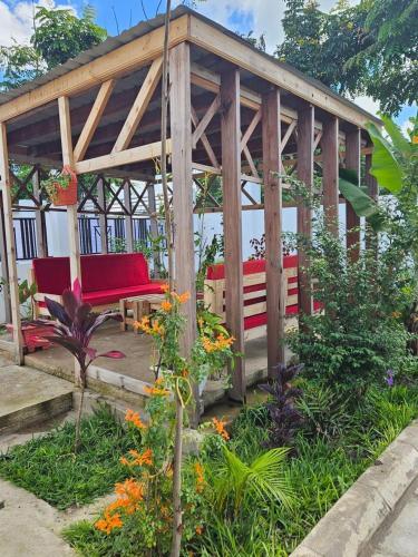a wooden gazebo with red benches in a garden at Welcome to Mkuki Hut in Arusha