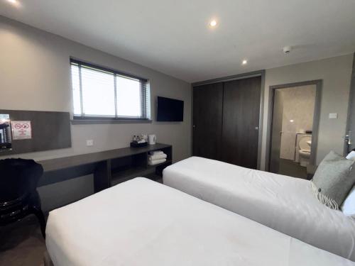 a hotel room with two beds and a desk at Richmond Park Hotel in Boʼness