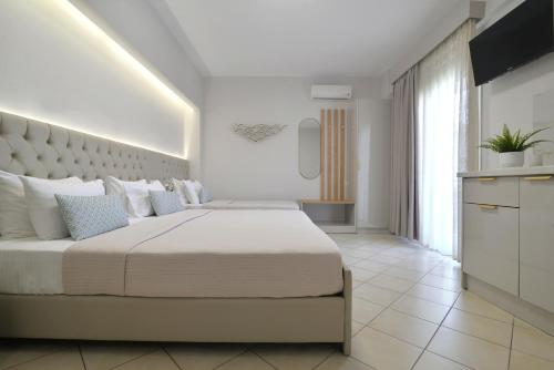 a white bedroom with a large bed and a large window at Irida Apartments in Leptokaria