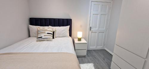a bedroom with a bed and a lamp on a night stand at Modern Living apartment in Balnacart