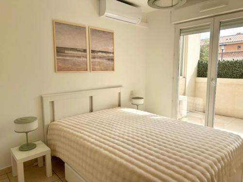 une chambre blanche avec un lit et une fenêtre dans l'établissement Appartement Cannes Grand Parc, à Cannes