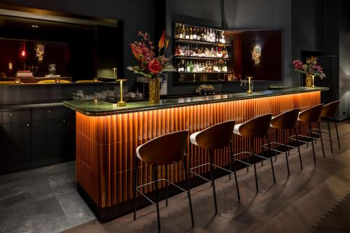 a bar with a row of bar stools at Hotel AMANO Düsseldorf in Düsseldorf