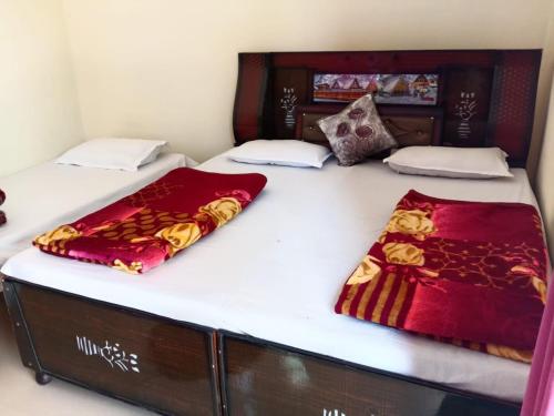two beds with white sheets and red blankets on them at Om som home stay hill view in Jāmb