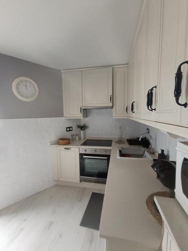 a kitchen with white cabinets and a clock on the wall at Rincón del Mar Terrazas y vistas a la Ría de Vigo in Moaña