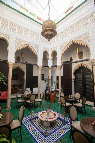 a large room with tables and chairs and a chandelier at Dar Lalzohra in Rabat