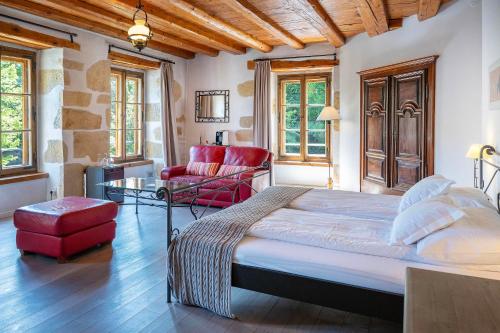 a bedroom with a large bed and a red chair at Hôtel La Maison du Prussien in Neuchâtel