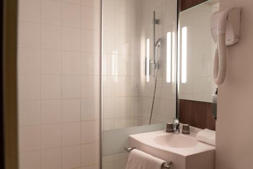 a white bathroom with a sink and a shower at IBIS STYLES Rouen Parc Expos Zenith in Saint-Étienne-du-Rouvray