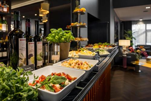 a buffet line with plates of food and wine bottles at Hotel AMANO Düsseldorf in Düsseldorf