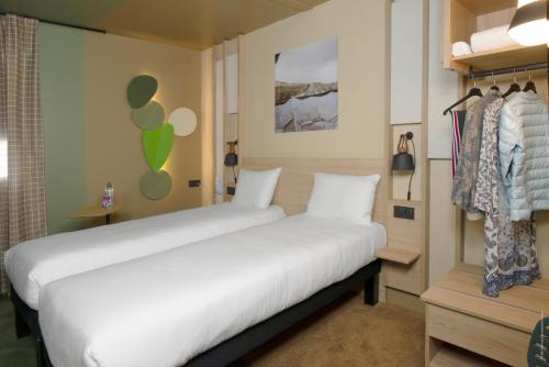 a bedroom with two beds and a closet at IBIS STYLES Rouen Parc Expos Zenith in Saint-Étienne-du-Rouvray
