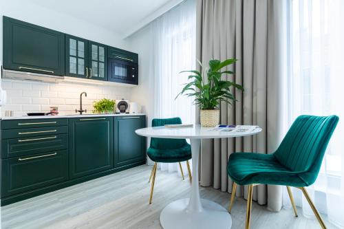 a kitchen with green cabinets and a table and chairs at Lapwing Residence Sopot in Sopot
