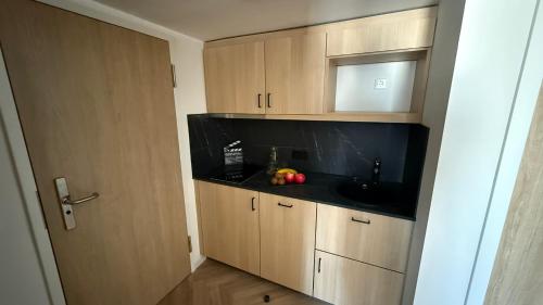 a kitchen with a sink and wooden cabinets at Cinema City Hotel Europaplatz Karlsruhe - Brand New Boutique Hotel 2025 - in Karlsruhe