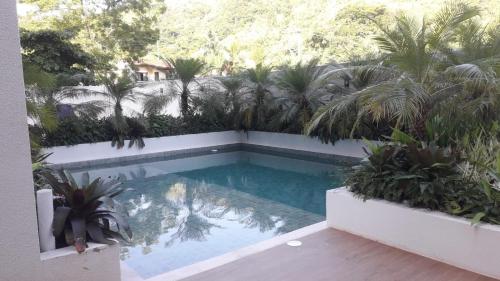 a swimming pool in a yard with palm trees at lindo apartamento martim de sá 2 dormitórios wi fi piscina pé na areia 32 b in Caraguatatuba