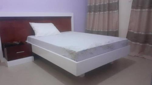 a large white bed in a room with curtains at Keur Massar tollou laye wade in Dakar