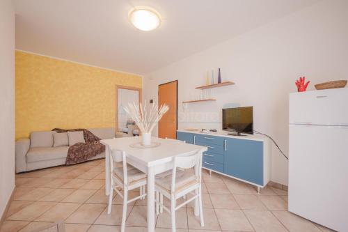 cocina y sala de estar con mesa y nevera en Residence Le Ginestre Mare, en Cavallino-Treporti